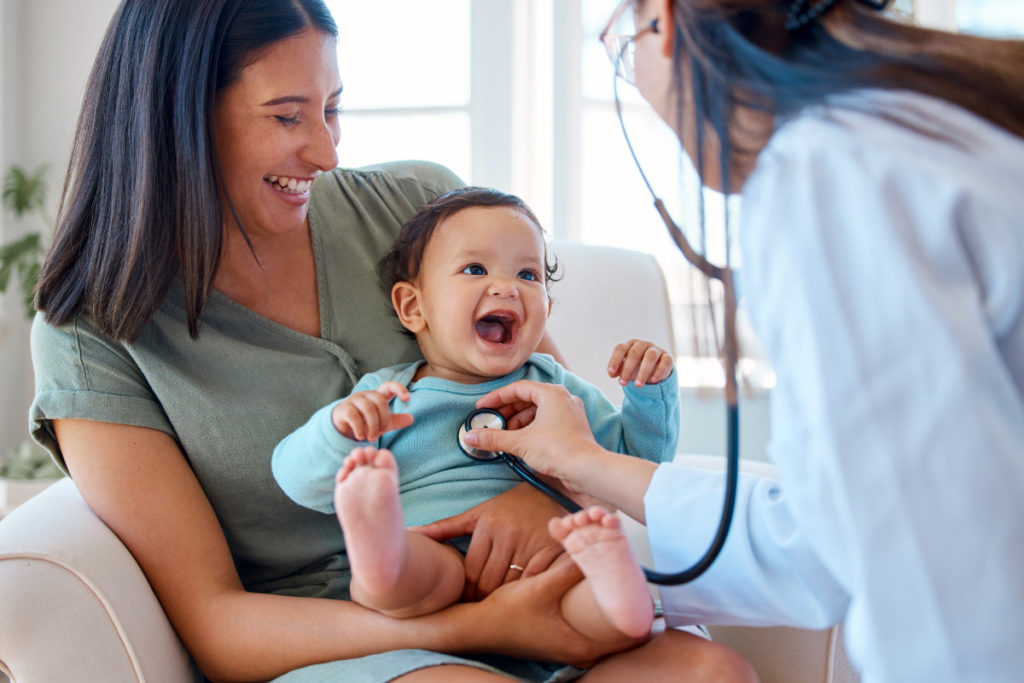 Shot of a baby sitting on her mother’s lap while being examined by a doctor
