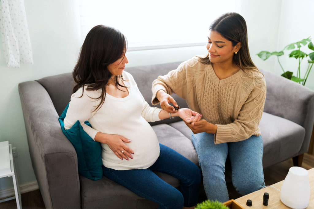 Happy doula using oils on a pregnant woman to improve her energy