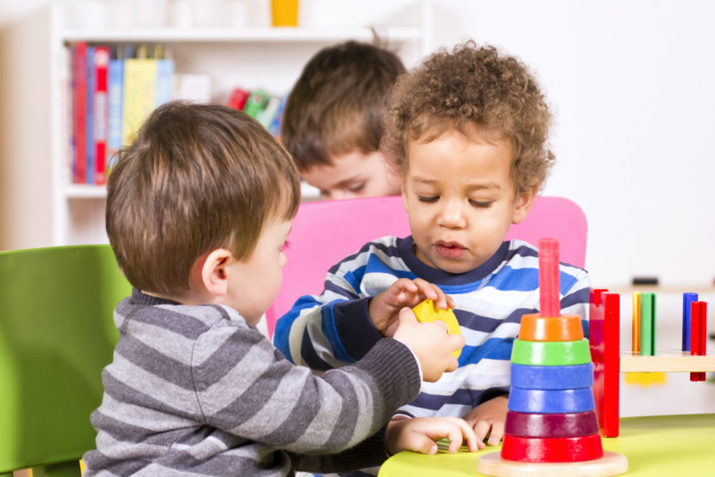 Toddlers helping and sharing in the playroom